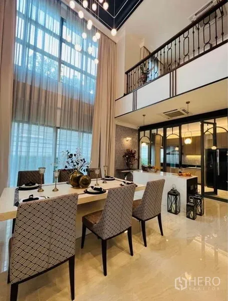 Detached House for rent or sale in Watthana, Bangkok - Dining area connected to a glass-partitioned kitchen and mezzanine balcony.