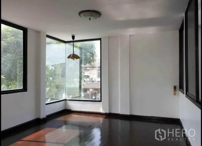 Detached House for rent in Lat Phrao, Bangkok - Corner room upstairs with large picture windows, pendant light and glossy dark wood floors.