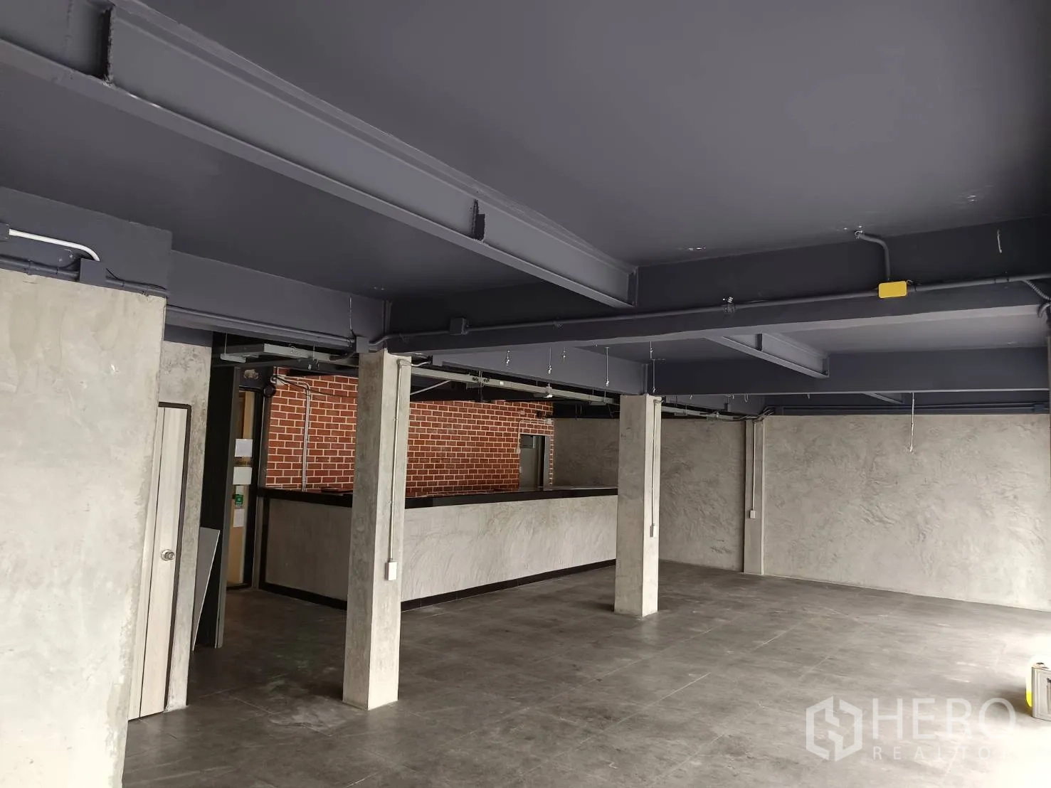 Retail Space for rent in Watthana, Bangkok - Spacious industrial-style room with exposed steel beams, concrete columns and grey walls.