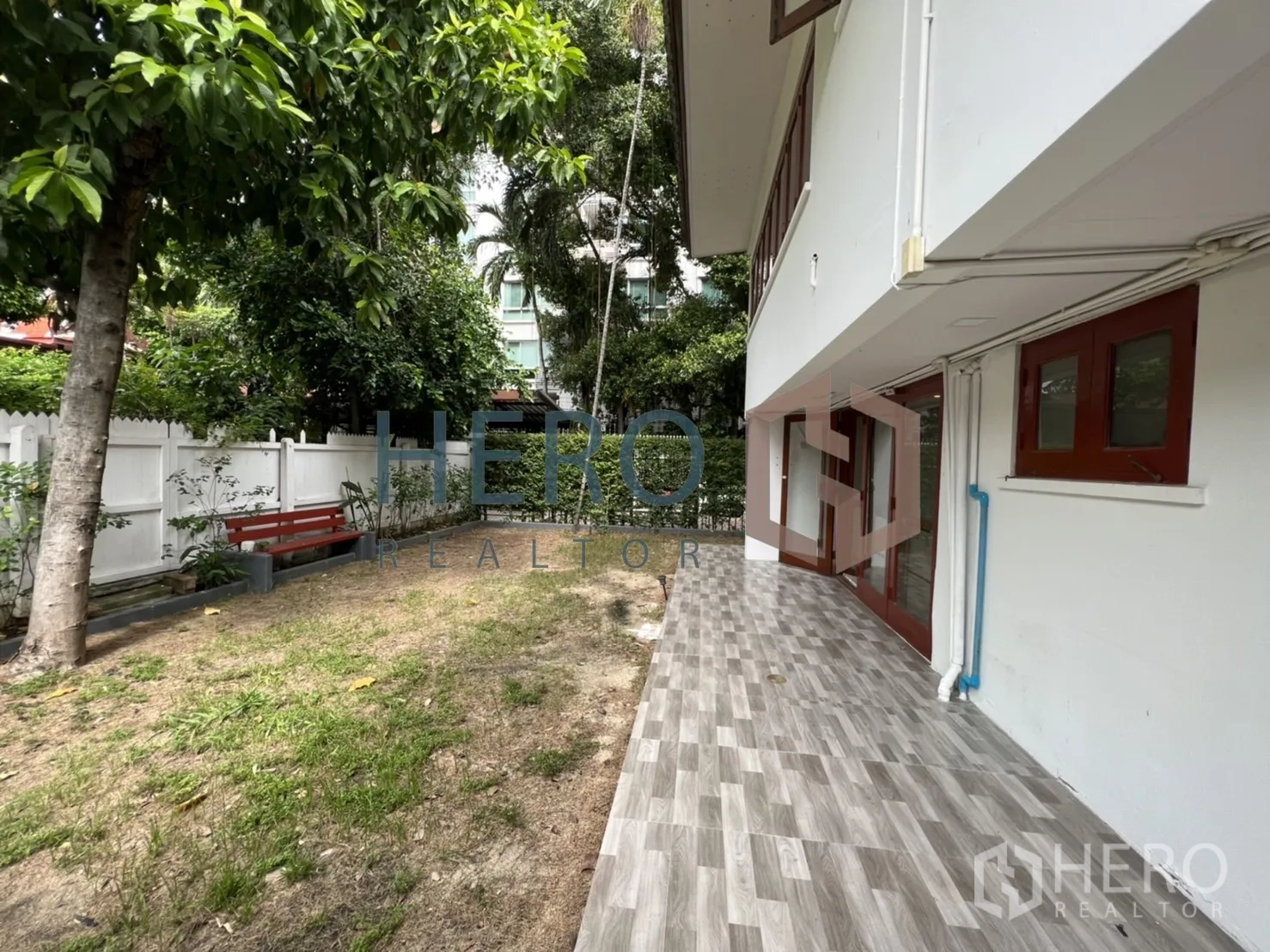 Detached House for rent in Watthana, Bangkok - Side terrace with grey tiles beside the lawn and white fence.