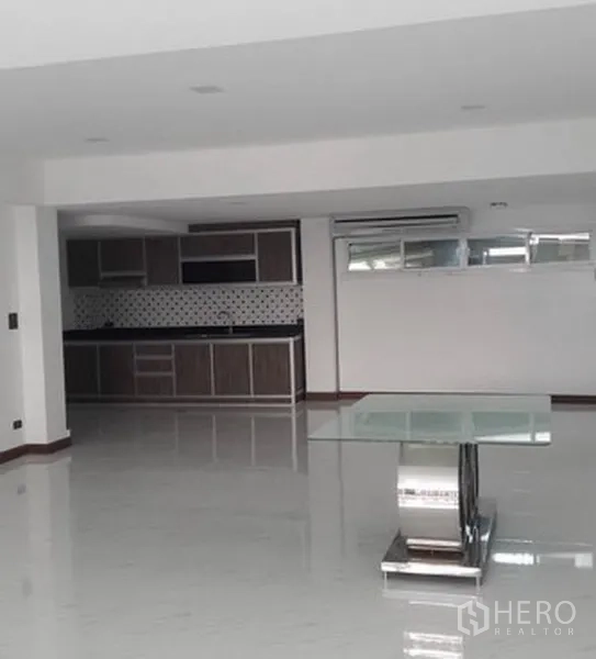 带办公室的家 出租在Khlong Toei, Bangkok - 宽敞的开放式起居区，亮面地板、玻璃桌与墙面一体式厨房