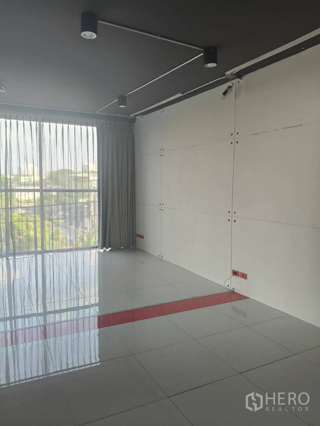Office Space for rent in Khlong Toei, Bangkok - Corner of open space showing large window, track lights and a clean white panel wall.