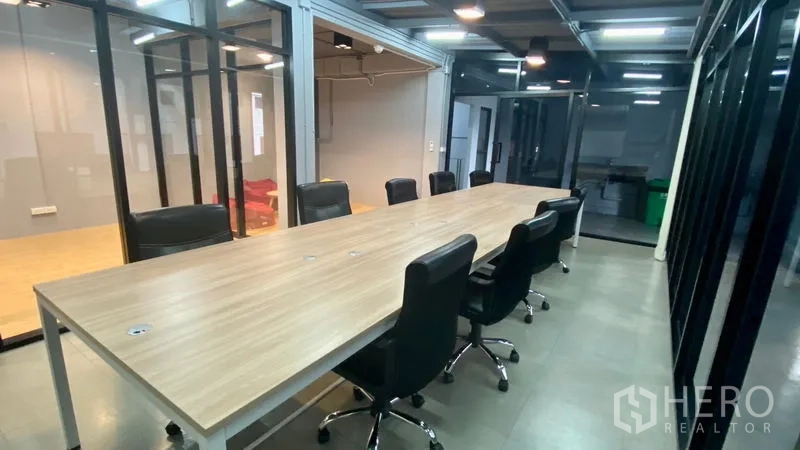Office Space for rent in Sathon, Bangkok - Open-plan meeting area with a long workstation table and framed glass walls for natural light.