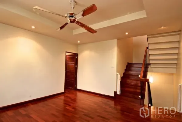 Detached House for rent in Watthana, Bangkok - Room with a wooden staircase, ceiling fan and recessed lights.