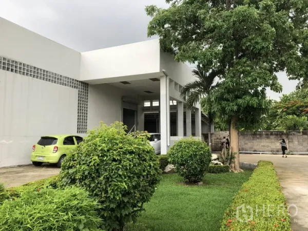 Factory for rent in Lat Krabang, Bangkok - Front entrance of the factory with canopy, green lawn and mature trees.