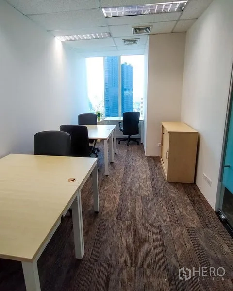 Office Space for rent in Khlong Toei, Bangkok - Narrow private office with desks, cabinet and skyline view through the window.