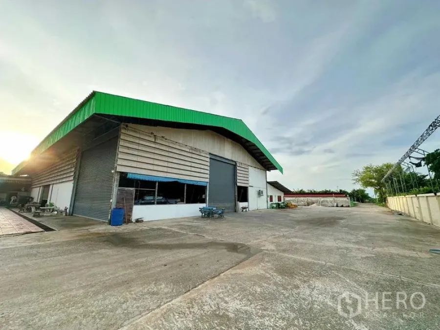 Warehouse for rent in Sai Noi, Nonthaburi - Exterior of the warehouse with expansive fenced yard suitable for truck turning and parking.