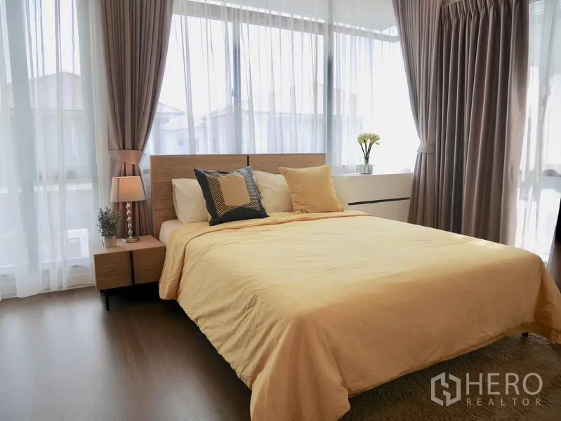 Detached House for rent in Bang Kapi, Bangkok - Second bedroom with large corner windows, warm yellow bedding and bedside lamps.