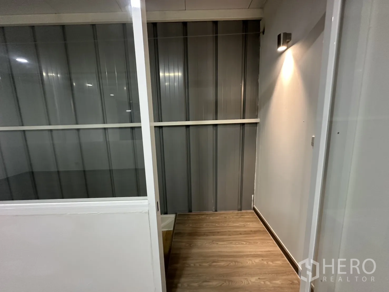 Warehouse for rent in Suan Luang, Bangkok - Compact corridor beside a glass partition with metal cladding wall, spotlight and vinyl plank flooring.