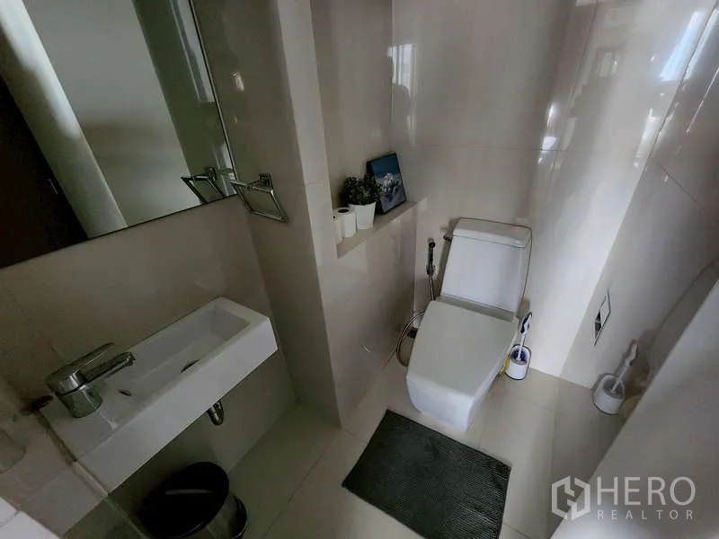 Condominium for sale - Contemporary bathroom with wall-mounted sink, mirror, tiled walls and a toilet with bidet spray.