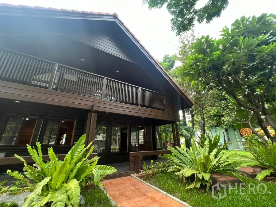 Home Office for rent in Suan Luang, Bangkok - Two-storey dark-wood home office with balcony, garden path and mature trees.