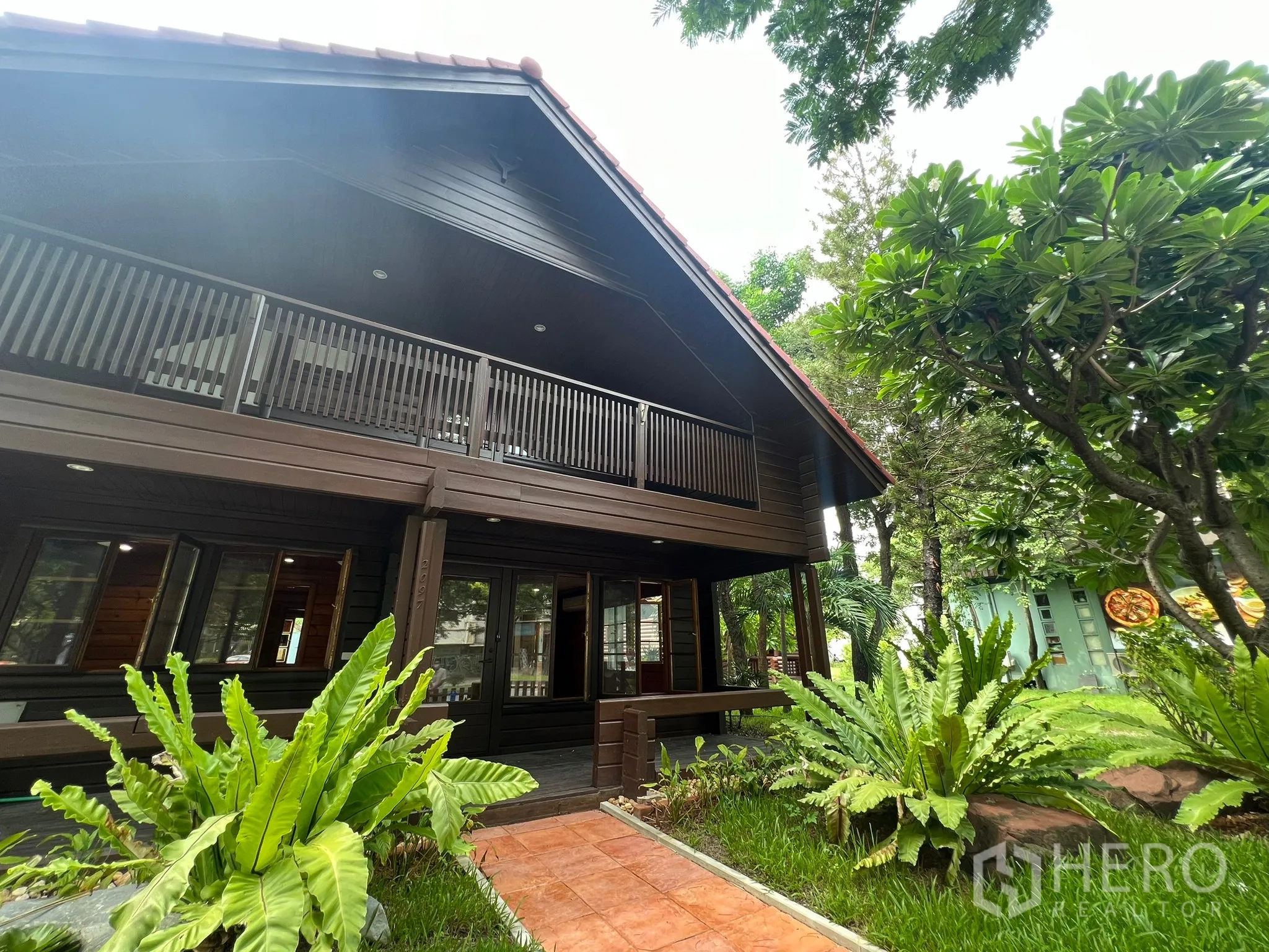 Home Office for rent in Suan Luang, Bangkok - Two-storey dark-wood home office with balcony, garden path and mature trees.