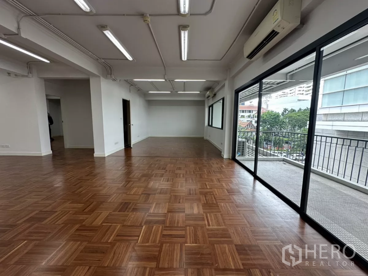Office Space for rent in Watthana, Bangkok - Bright open office with full-length glass, balcony railing and air-conditioning units.