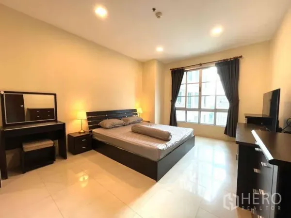 Apartment for rent in Khlong Toei, Bangkok - Spacious master bedroom with king bed, vanity and large curtained window.