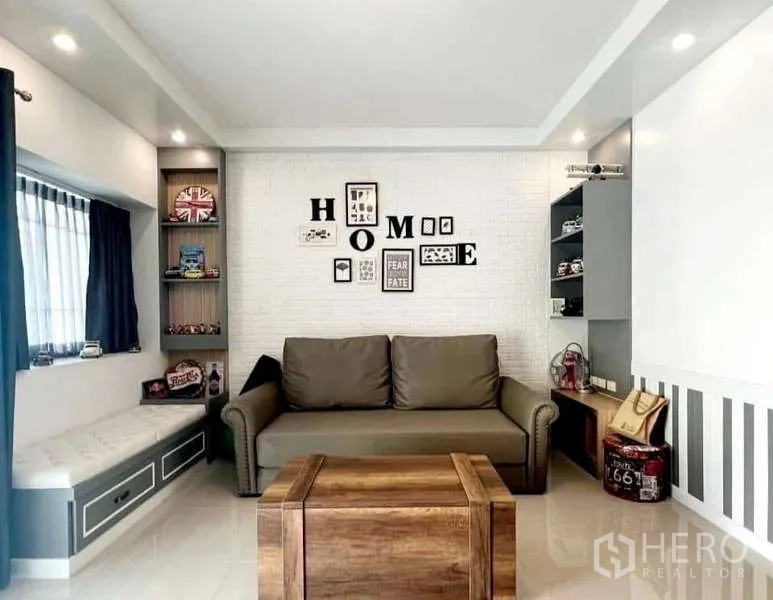 Detached House for rent in Bang Phli, Samut Prakan - Modern living room with sofa, display shelves and white brick feature wall.