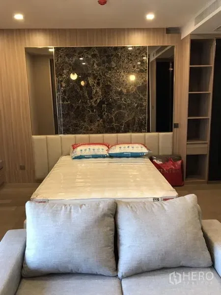 Condominium for rent in Watthana, Bangkok - Cozy bedroom zone with marble accent wall, built-in wardrobe and sofa in a 1-bedroom condo near Asok.