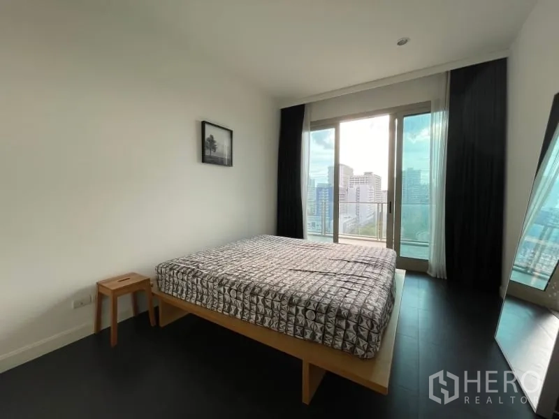 Condominium for rent or sale in Pathum Wan, Bangkok - Bright bedroom with balcony access, large window and city skyline view with minimalist decor.