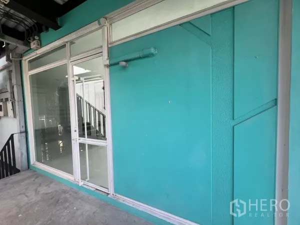 Retail Space for rent in Watthana, Bangkok - Turquoise exterior wall with wide glass shopfront and door along an upper-level walkway.