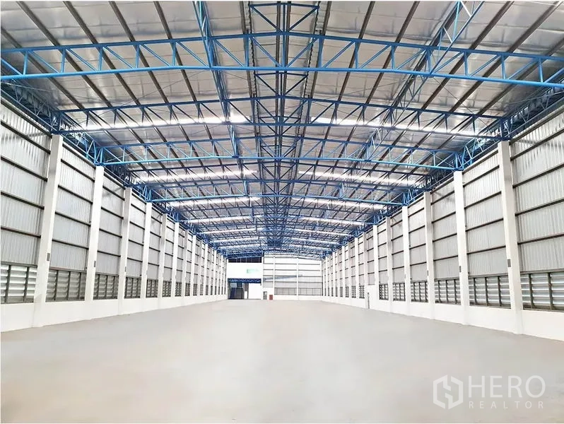 Warehouse for rent in Lat Krabang, Bangkok - Clear-span warehouse interior featuring an insulated high roof with blue steel trusses and polished concrete flooring.
