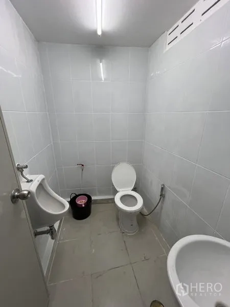 Warehouse for rent in Saphan Sung, Bangkok - Clean tiled restroom inside the warehouse with toilet, urinal, sink and ceiling light