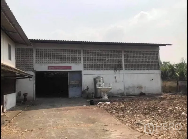 Factory for sale in Nong Chok, Bangkok - Single-storey factory exterior with roller door and paved loading area.