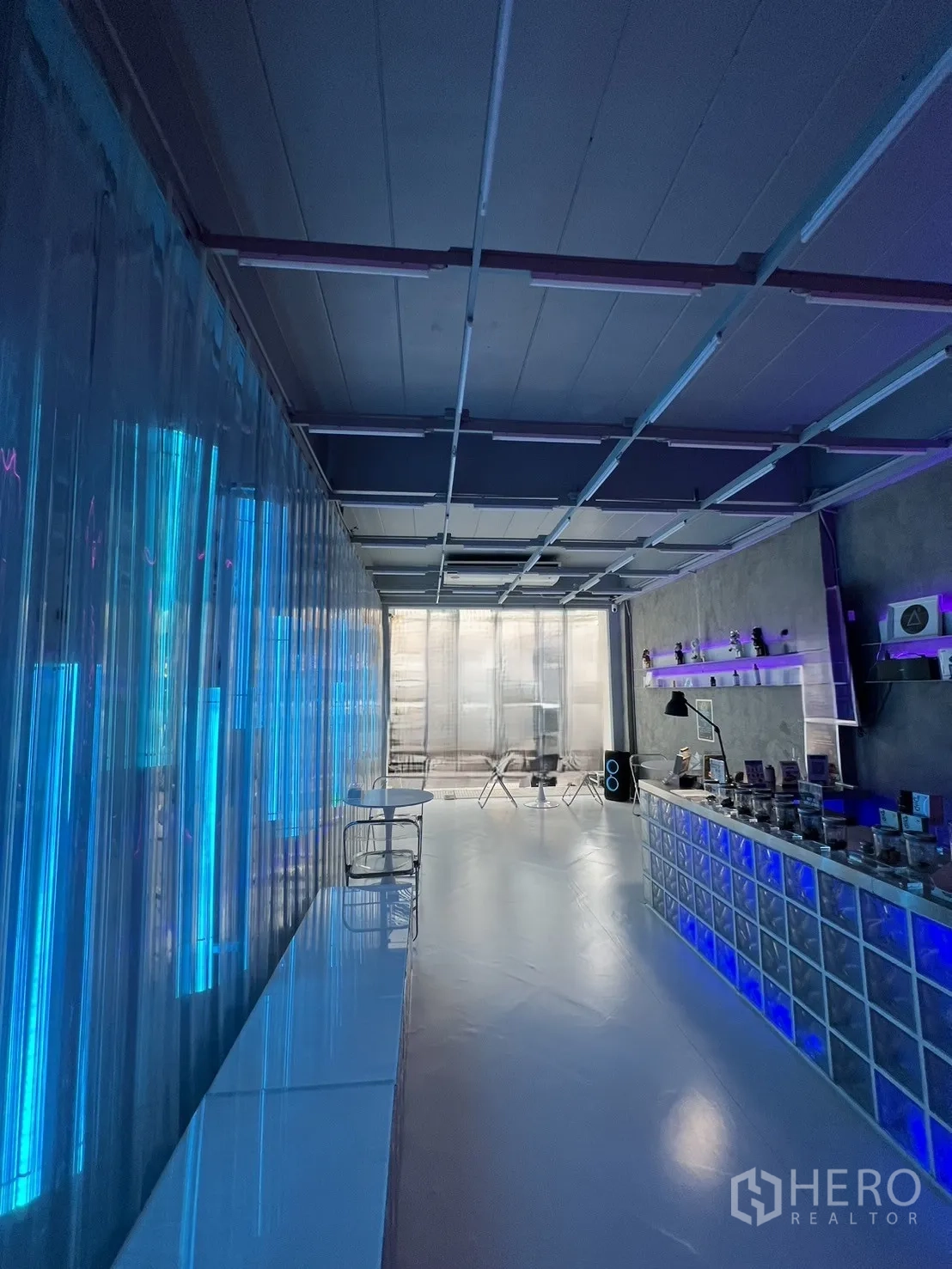 Shophouse for rent or sale in Watthana, Bangkok - Ground floor retail hall with blue neon lighting, glass-block counter and polished floor.