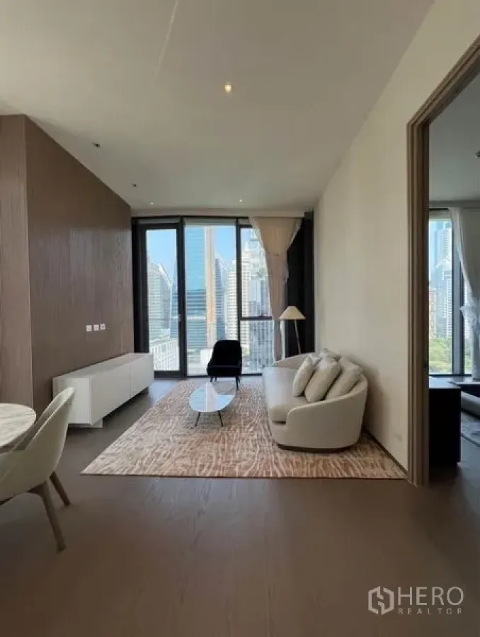 Condominium for rent - Cozy lounge with curved sofa, rug, and balcony doors overlooking the city skyline.