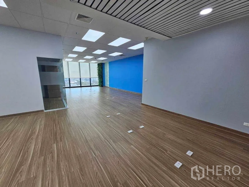 办公空间 出租在Sathon, Bangkok - 开放工位区，蓝色特色墙与靠窗垂直绿植景观