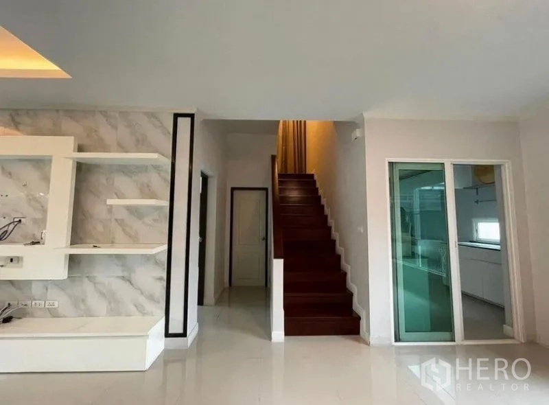 Detached House for sale in Bang Phli, Samut Prakan - Wooden staircase beside a sliding door leading to the separate kitchen and hallway.