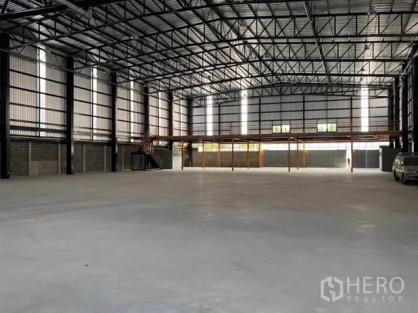 Warehouse for rent in Khlong Toei, Bangkok - Spacious high-clearance warehouse interior with steel truss roof, polished concrete floor and a rear mezzanine platform.