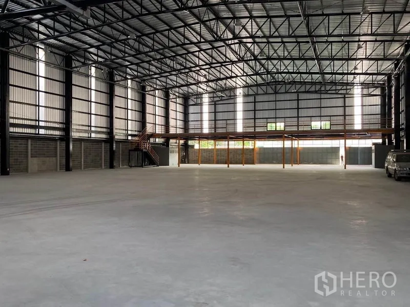 Warehouse for rent in Khlong Toei, Bangkok - Spacious high-clearance warehouse interior with steel truss roof, polished concrete floor and a rear mezzanine platform.