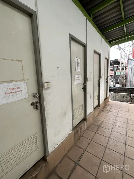 Warehouse for rent in Lat Krabang, Bangkok - Row of separate restroom doors along a tiled corridor beside the warehouse.