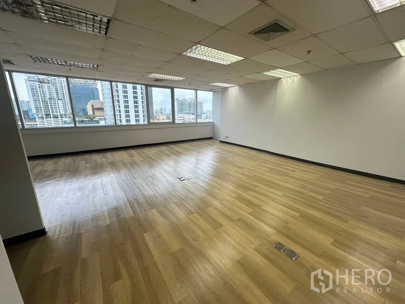 Office Space for rent in Phra Khanong, Bangkok - Corner office area showcasing Bangkok skyline through big windows and suspended ceiling lights.