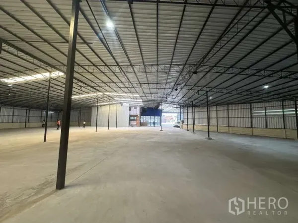 货栈 出租在Pak Kret, Nonthaburi - 高挑仓库大厅，成排立柱，尽头为玻璃入口。