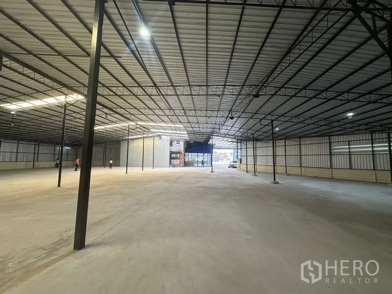 货栈 出租在Pak Kret, Nonthaburi - 高挑仓库大厅，成排立柱，尽头为玻璃入口。