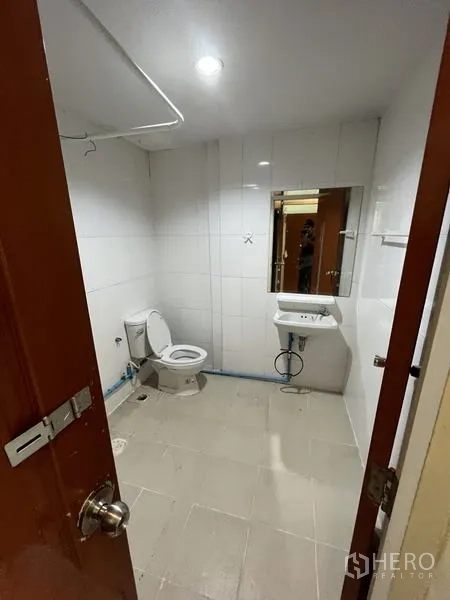 店屋 for rent in Khlong Toei, Bangkok - 浴室铺白色墙砖，配坐便器、洗手盆与镜子。