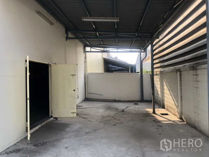Factory for rent in Khlong Luang, Pathum Thani - Covered loading bay with metal roof, concrete floor and side access door.