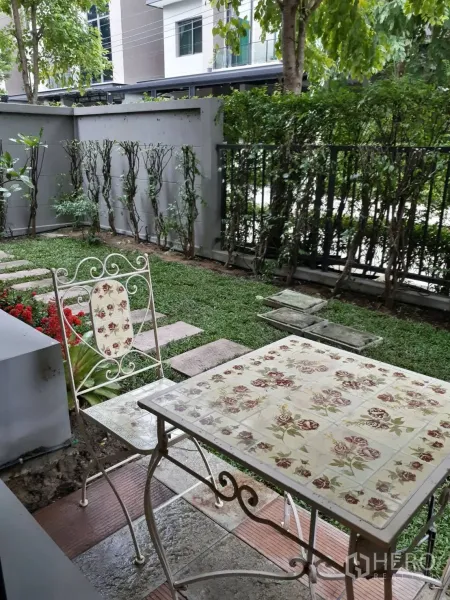Townhouse for rent in Bang Kapi, Bangkok - Shaded private garden with wrought-iron table, chairs, hedges and a stone path.