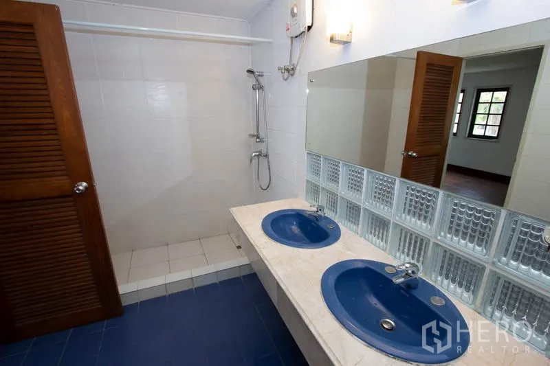 Townhouse for rent in Khlong Toei, Bangkok - Bathroom with double blue basins, wide mirror and walk-in shower.