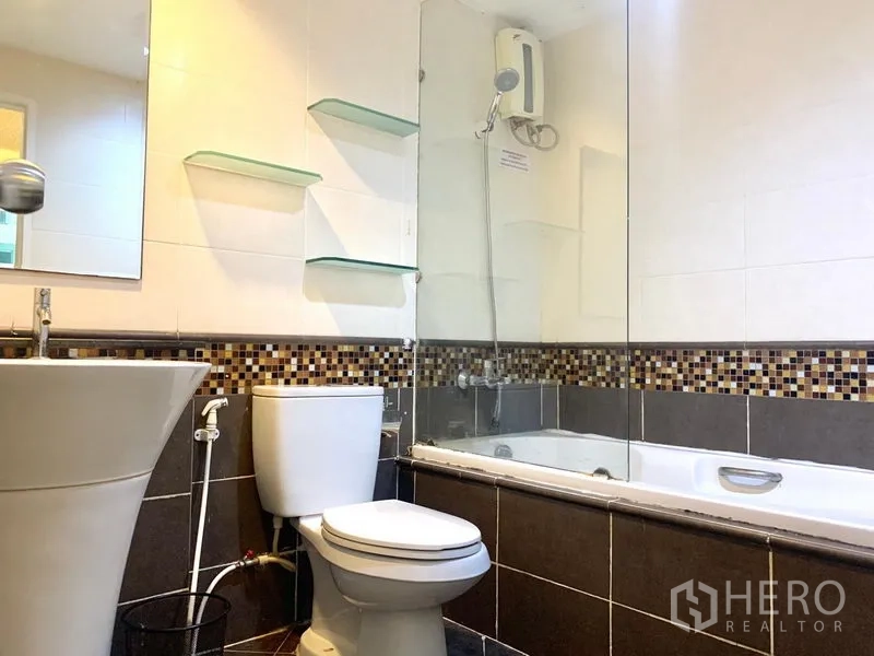 Condominium for rent in Khlong Toei, Bangkok - Bathroom with bathtub, shower, glass partition and mosaic tile accent.