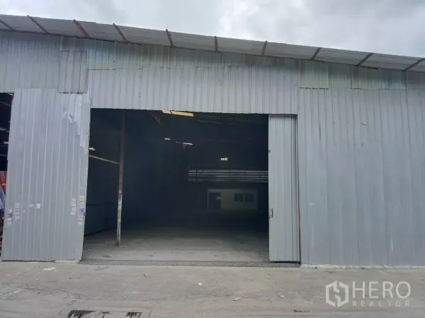货栈 出租在Saphan Sung, Bangkok - 金属外墙仓库外观，超宽滑动门与混凝土前场，天空多云