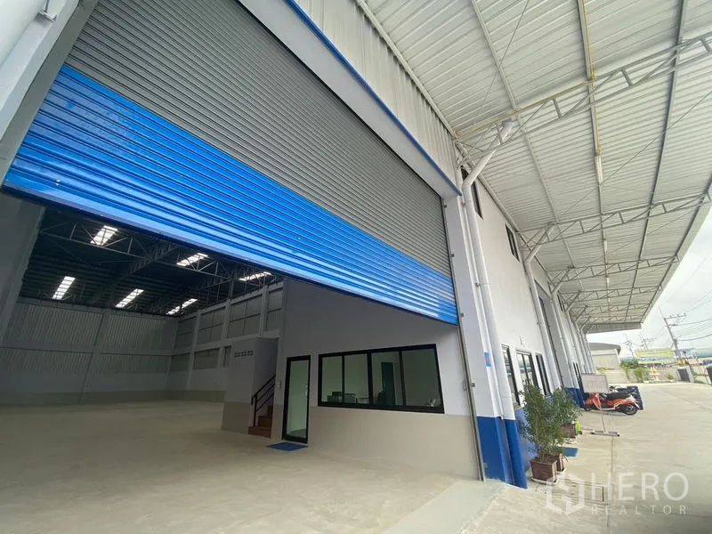 货栈 出租在Pathum Thani - 入口装卸位，升起的卷帘门、办公窗与带雨棚的平台。