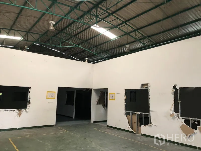 Factory for rent in Pathum Thani - Factory interior showing high steel-truss ceiling, partitioned rooms and solid concrete floor.