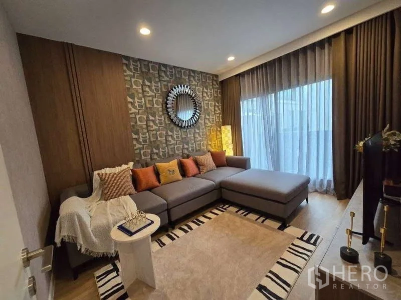 Detached House for rent in Bang Kapi, Bangkok - Family room with large L-shaped sofa, patterned rug and sliding glass door.