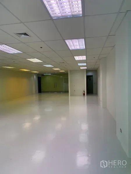 Office Space for rent in Watthana, Bangkok - Open-plan white office with suspended ceiling lights, glossy floor, and a glass entry.