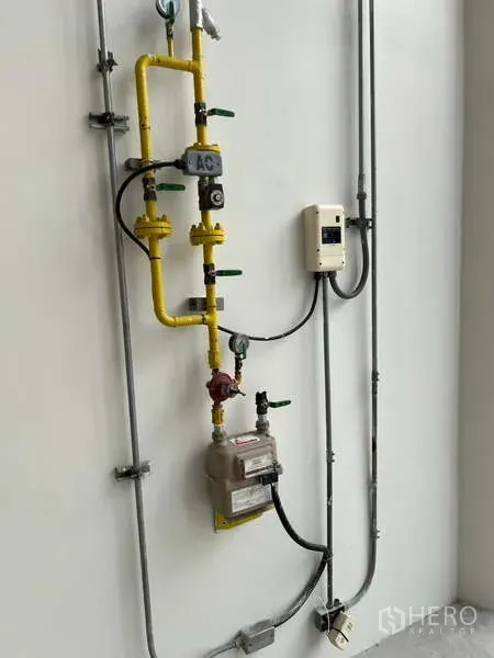 Retail Space for rent in Phaya Thai, Bangkok - Close‑up of utility installation showing yellow gas pipe, valves, meter and control box on a white wall.