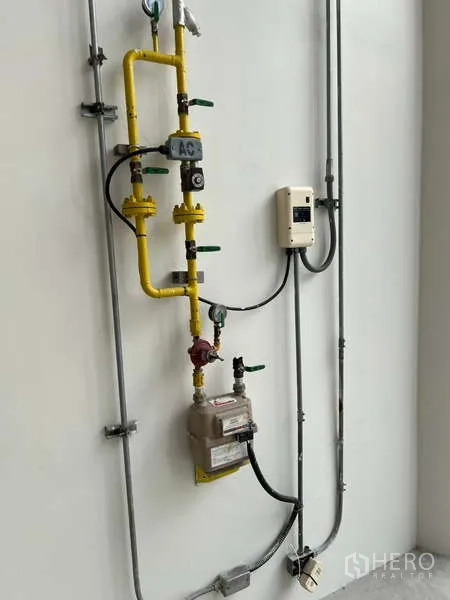 Retail Space for rent in Phaya Thai, Bangkok - Close‑up of utility installation showing yellow gas pipe, valves, meter and control box on a white wall.