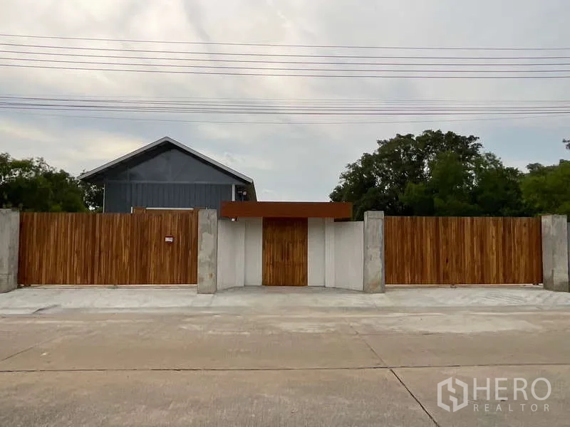 Warehouse for rent or sale in Nong Chok, Bangkok - Modern wooden entrance gate and wide driveway leading into a secure warehouse compound.