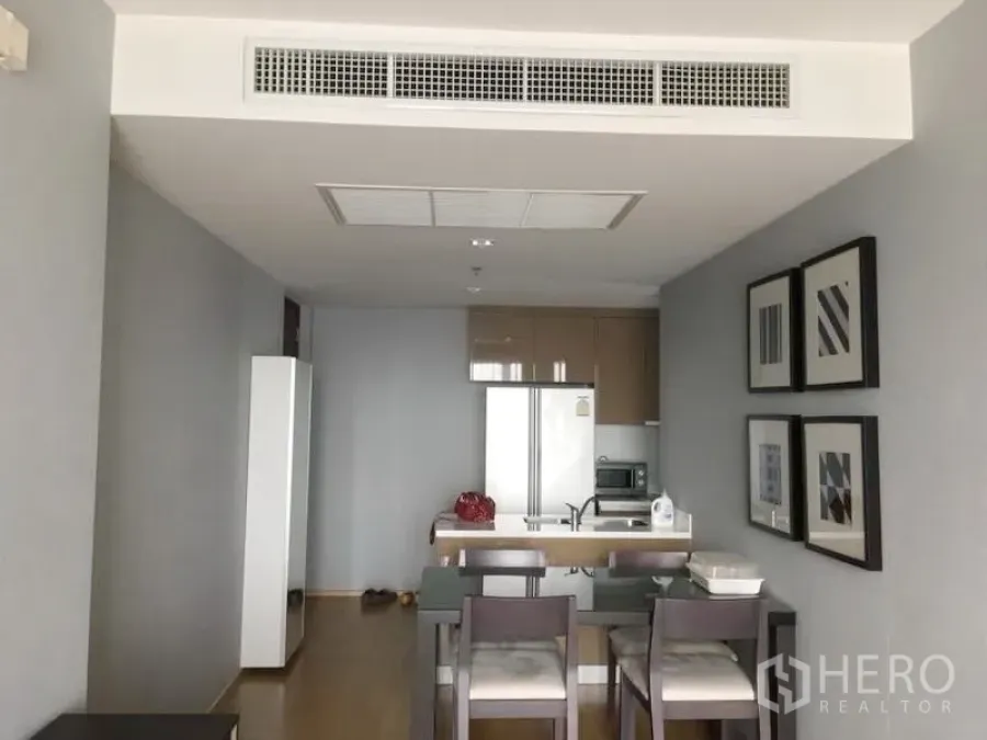 Condominium for rent in Khlong Toei, Bangkok - Open-plan dining and kitchen with four-seat table, island counter, built-in cabinets, large fridge and ducted air conditioning.