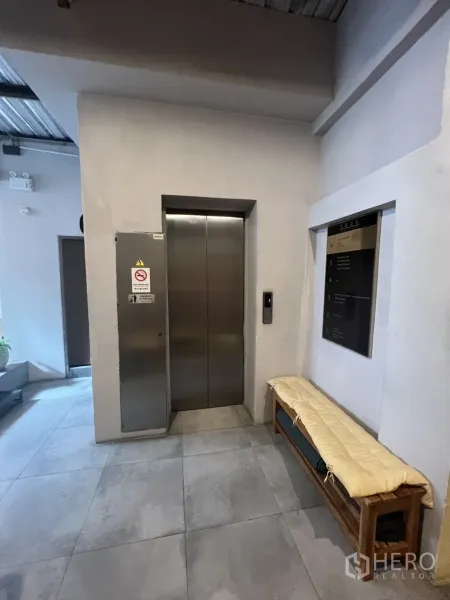 Retail Space for rent - Building lobby with a stainless-steel elevator, bench seating and large ceramic floor tiles.